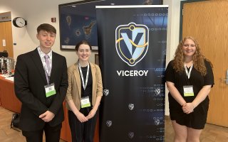 UAlbany students stand in front of VICEROY step and repeat banner.